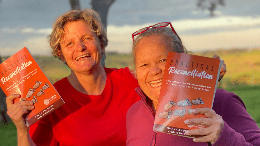 Picture of Carla Rogers and Aunty Munya Andrews holding up a copy of their book, 'Practical Reconciliation'
