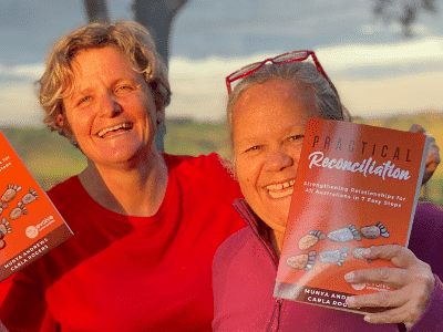 Aunty Munya and Carla holding up their book, Practical Reconciliation